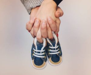 Future parents holding a pair of little shoes stock photo